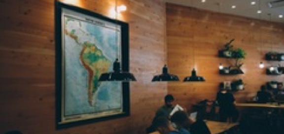 view of the inside of a study lounge with low-hanging lights and a map of South America framed on the wall