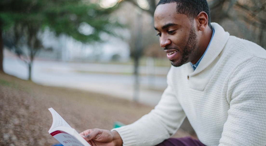 a student reading outdoors with an unfocued background