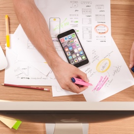 aerial view of an arm highlighting paper notes with a smartphone located in the middle of the pile